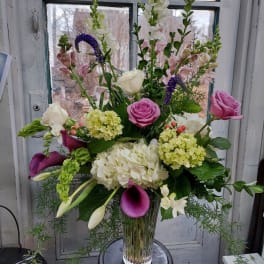 Mixed bouquet with roses, hydrangeas, calla lilies, and snapdragons in a glass vase