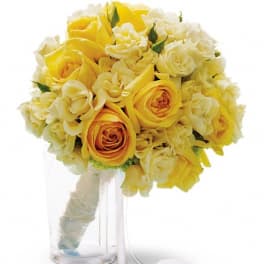 Yellow and white rose bouquet in a clear glass vase with ribbon
