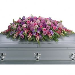 Pink and purple floral spray arranged on a gray casket