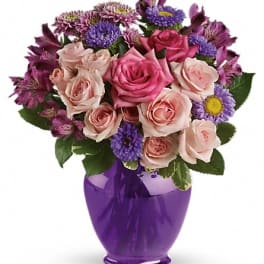 Pink and purple mixed flower bouquet in a purple vase