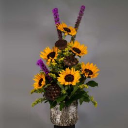 Sunflowers and purple spikes arranged in a birch bark container