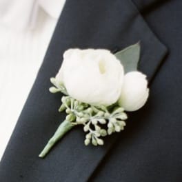 White boutonniere pinned to a dark suit lapel