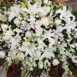 Large white floral spray with lilies, orchids, and roses