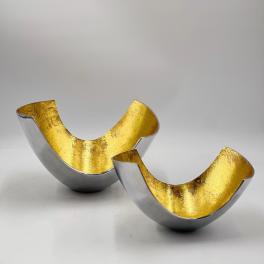 Two metallic gold and silver decorative bowl-shaped objects on a white surface