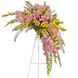 Pink and yellow floral spray on a white easel stand
