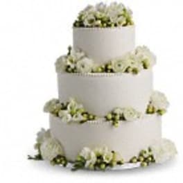 Three-tier white wedding cake decorated with white flowers