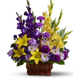 Purple and yellow mixed flower arrangement in a wicker basket