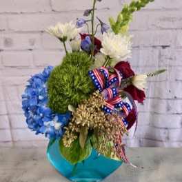 Mixed bouquet with blue, white, red, and green flowers in a blue vase