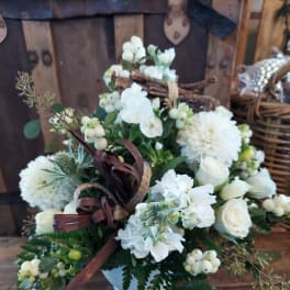 White floral arrangement in a white vase with berries and ribbon