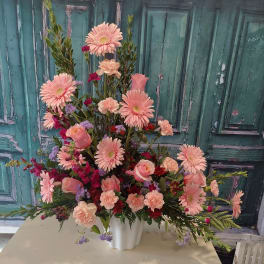 Large pink floral arrangement in a white vase
