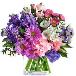 Mixed bouquet of purple, pink, white, and blue flowers in a clear glass vase