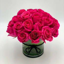 Bouquet of hot pink roses in a green glass vase with a black ribbon