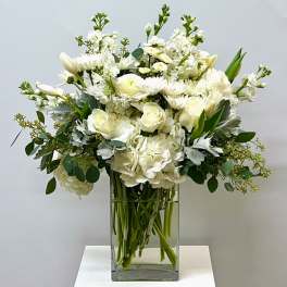 White roses and hydrangeas in a clear glass vase