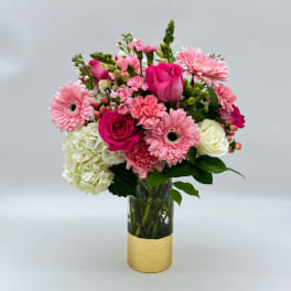 Pink and white mixed bouquet in a clear glass vase with a gold wrap