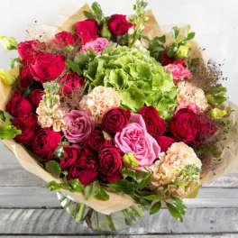 Bouquet of red and pink roses with green hydrangea in paper wrap