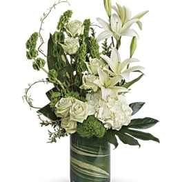 White lilies and roses arranged in a green glass vase