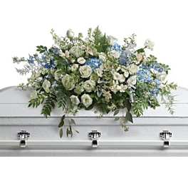 White and blue floral casket spray on a white coffin