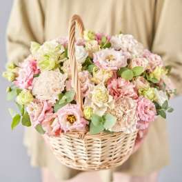 Basket of pastel pink and cream flowers with greenery