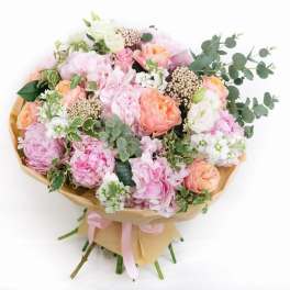 Bouquet of pink and peach flowers with eucalyptus wrapped in tan paper