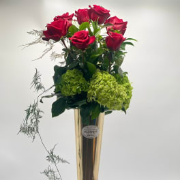 Tall vase arrangement with red roses and green hydrangeas
