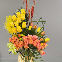Mixed bouquet of yellow and peach flowers in a striped vase