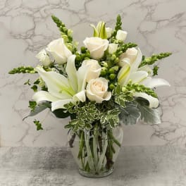 White roses and lilies arranged in a clear glass vase