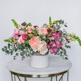 Pink and peach floral arrangement in a white vase
