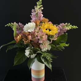 Mixed bouquet in a striped vase with sunflowers, snapdragons, and carnations