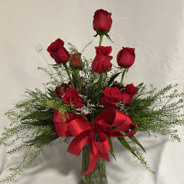 Red roses arranged in a clear glass vase with a large red ribbon