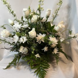 White roses and daisies in a low, full arrangement with tall white spikes
