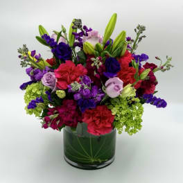 Colorful bouquet of lilies, roses, and carnations in a glass vase