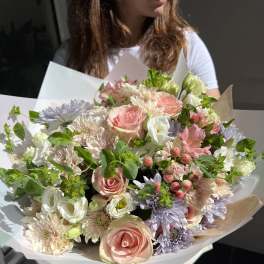 Large pastel bouquet of roses, chrysanthemums, and white blooms wrapped in paper