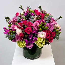 Mixed pink and purple flower arrangement in a dark glass vase