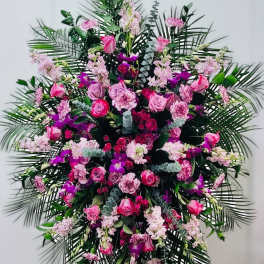 Large standing spray of pink and purple flowers with palm fronds