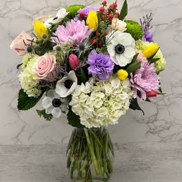 Mixed bouquet of pastel flowers in a clear glass vase