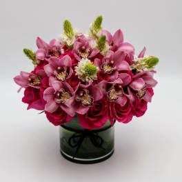 Pink orchids and roses arranged in a glass vase