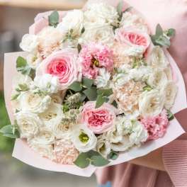Pink and white bouquet of roses and carnations wrapped in pale paper