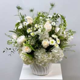 White roses and hydrangeas arranged in a white vase