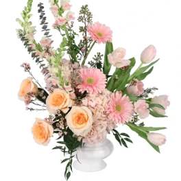 Pink and peach floral arrangement in a white pedestal vase