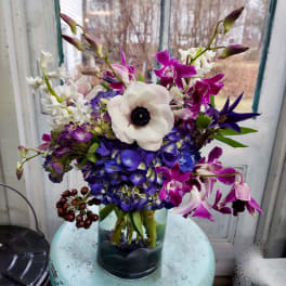 Bouquet of purple, white, and blue flowers in a glass vase