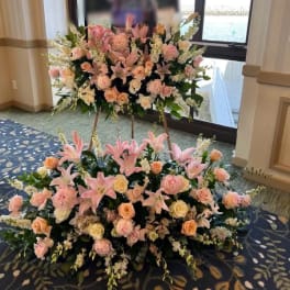 Large pink and peach floral funeral display on easels