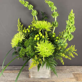 Lime green floral arrangement in a wooden box with tall blooms and berries