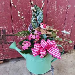 Pink flowers in a mint watering can with a gingham bow and bird decoration
