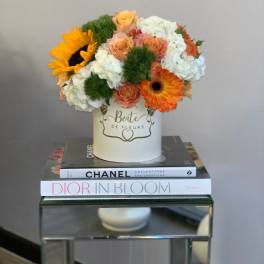 Bouquet of orange and white flowers in a white hat box