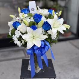 Blue and white bouquet with lilies and roses in a glass vase