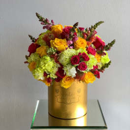 Bright mixed bouquet in a gold hatbox with yellow and pink flowers