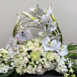 White orchid and rose floral arrangement in a woven basket