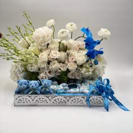 White rose arrangement with blue orchids and small teddy bears in a gift box