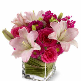 Pink lilies and roses in a clear square vase