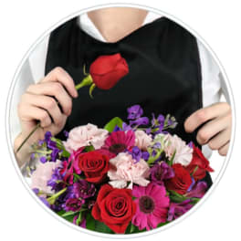 Person holding a bouquet of red, pink, and purple flowers